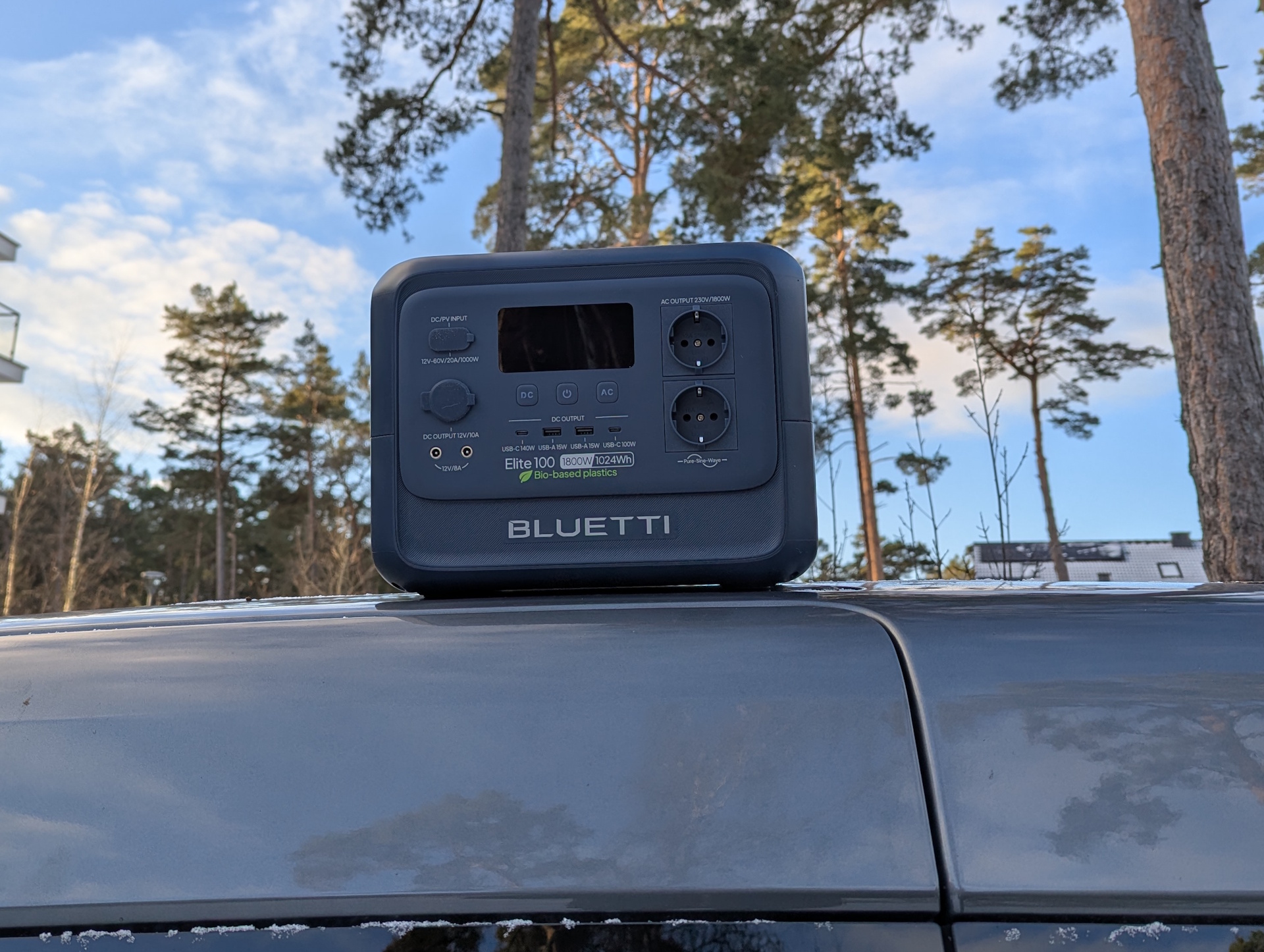 Bluetti Elite 100 V2 Bio-based em um teto de carro com pinheiros ao fundo