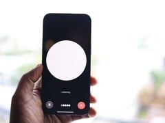 Uma mão segurando um smartphone com uma interface de assistente de voz na tela