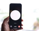 Uma mão segurando um smartphone com uma interface de assistente de voz na tela