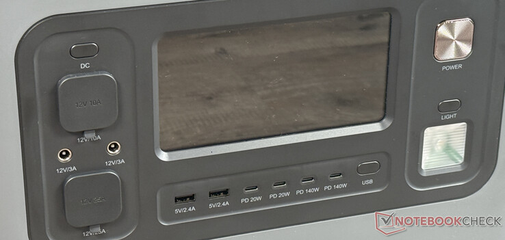 Na parte frontal: tela, 6 portas USB e outras portas CC, botão liga/desliga e luz LED