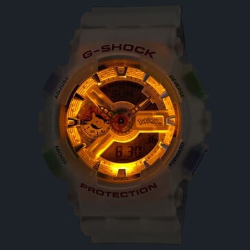 O relógio Casio G-Shock Pokémon GA-110 com a luz de fundo LED âmbar acesa em um ambiente escuro.