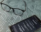 Smartphone com o aplicativo ChatGPT aberto ao lado de um par de óculos sobre uma superfície estampada