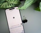 Smartphone com o aplicativo ChatGPT aberto, apoiado em um laptop ao lado de folhas de plantas