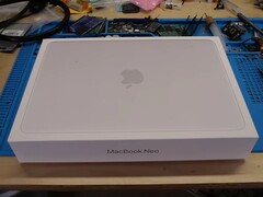 Caixa de varejo do MacBook Neo colocada em uma bancada de trabalho antes da desmontagem para atualização do SSD