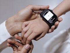 A mão de um adulto colocando um smartwatch no pulso de uma criança