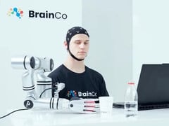 Um usuário da tecnologia de controle mental da BrainCo pegando uma maçã de forma robótica, apenas com o pensamento.