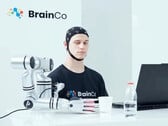 Um usuário da tecnologia de controle mental da BrainCo pegando uma maçã de forma robótica, apenas com o pensamento.