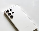 Smartphone Samsung Galaxy branco com quatro câmeras traseiras sobre uma superfície clara.