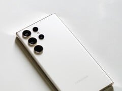 Smartphone Samsung Galaxy branco com quatro câmeras traseiras sobre uma superfície clara.