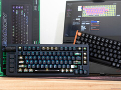 Teclados de efeito Hall Lemokey L1 HE Keychron K4 HE em uma mesa, em frente a uma caixa e um laptop