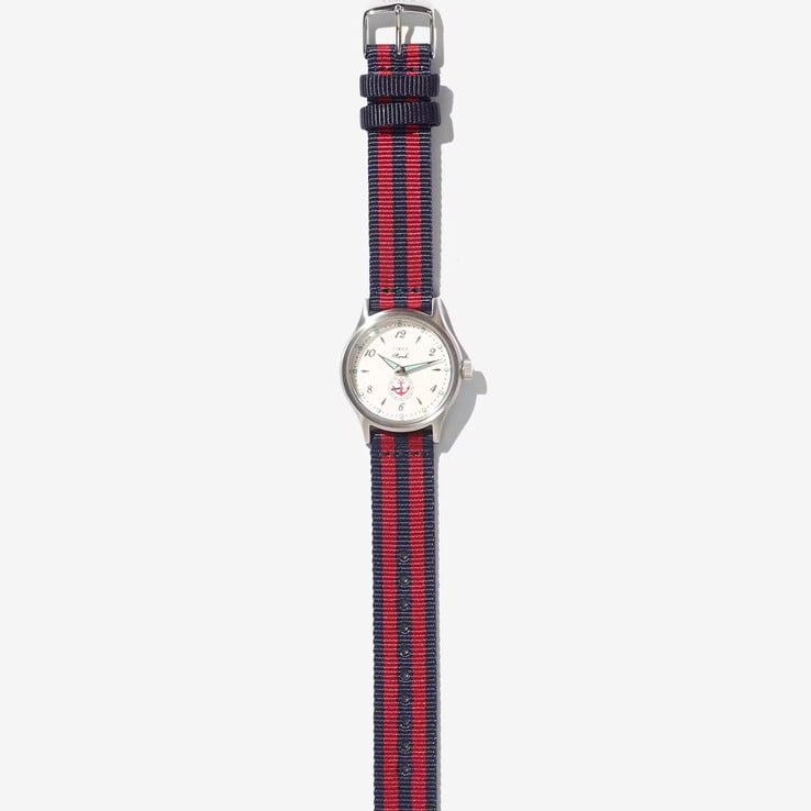 Relógio Noah x Timex MK1 Anchor com caixa prateada de 36 mm, mostrador creme, desenho de âncora e pulseira de tecido listrada em azul-marinho e vermelho.