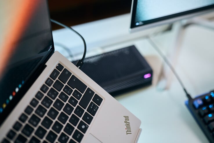 Foto em close-up de um cabo Thunderbolt 5 conectado à porta lateral de um laptop Lenovo ThinkPad X9, com a eGPU Aorus ao fundo.