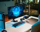 Uma configuração de gaming minimalista em estúdio, com o monitor Sony Inzone M10S II sobre uma mesa branca, ao lado de um console PlayStation 5 Pro na vertical, teclado mecânico, mouse sem fio e fone de ouvido com uma discreta iluminação azul.
