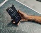 Mão segurando um smartphone com o aplicativo ChatGPT aberto sobre uma mesa estampada