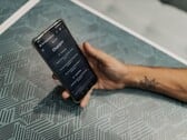 Mão segurando um smartphone com o aplicativo ChatGPT aberto sobre uma mesa estampada