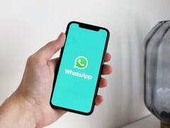 Mão a segurar um smartphone com a aplicação WhatsApp aberta
