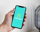Mão a segurar um smartphone com a aplicação WhatsApp aberta