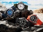 Quatro relógios de mergulho Citizen Promaster Marine nas cores branca, preta, azul e laranja, expostos sobre rochas à beira-mar.