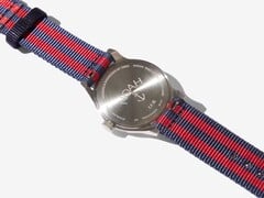 Vista traseira do relógio Noah x Timex MK1 Anchor, mostrando seu fundo de caixa em aço inoxidável gravado e a pulseira de tecido nas cores azul-marinho e vermelho.
