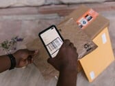 Uma mão segura um smartphone sobre um pacote e escaneia seu código de barras.