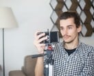 Um jovem se filma em casa com um smartphone montado em um tripé