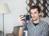 Um jovem se filma em casa com um smartphone montado em um tripé