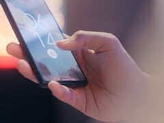 Uma mão segura um smartphone e o desbloqueia usando o sensor de impressão digital na tela de bloqueio.