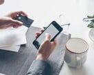 Pessoa digitando em um smartphone enquanto segura um cartão bancário na outra mão