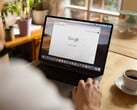 Pessoa usando um laptop com a página inicial do Google aberta, ao lado de uma xícara de café