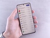 Uma mão segura um smartphone que exibe uma lista de atualizações na tela.