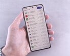 Uma mão segura um smartphone que exibe uma lista de atualizações na tela.