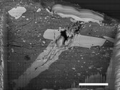 Imagem de microscópio eletrônico de varredura de uma cratera de impacto de micrometeorito em uma partícula de material do asteroide Bennu (Fonte da imagem: NASA, e Zia Rahman)