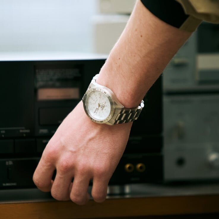 O HDB007 combina um mostrador branco prateado com um bezel de bússola em aço escovado
