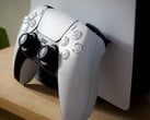 Uma imagem de um controle DualSense do PlayStation 5 apoiado em um console PS5