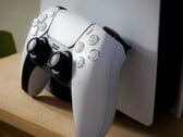 Uma imagem de um controle DualSense do PlayStation 5 apoiado em um console PS5