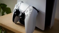 Uma imagem de um controle DualSense do PlayStation 5 apoiado em um console PS5