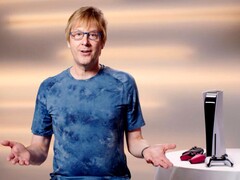 Mark Cerny durante um evento do PlayStation, sentado ao lado de um console PS5 e de controles DualSense. (Fonte da imagem: Sony Interactive Entertainment)