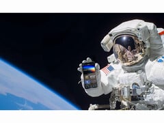 Uma imagem promocional do serviço gratuito NASA+ mostrando um astronauta segurando um smartphone com o aplicativo NASA+ aberto no espaço. (Fonte da imagem: NASA)