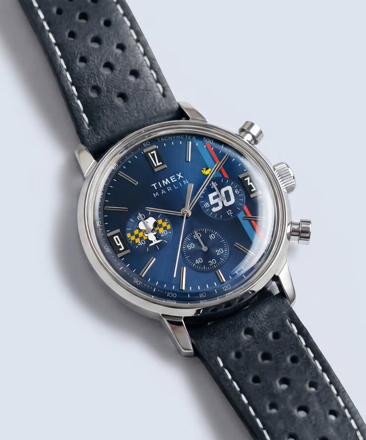 O cronógrafo Timex Peanuts x Marlin é mostrado em ângulo, com sua caixa de aço inoxidável polido, mostrador azul com efeito raios de sol e pulseira de couro azul perfurada.