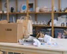 Caixa de papelão e sacolas de papel sobre uma mesa de madeira em um escritório com prateleiras