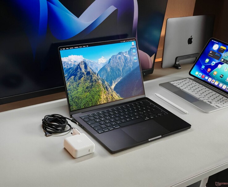 Apple MacBook Pro mostrado em uma mesa com carregador e monitores externos (Fonte da imagem: Notebookcheck)