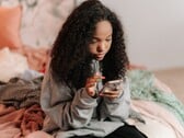 Adolescente usando um smartphone em uma cama, imagem simbólica do ChatGPT for Teens e dos controles parentais