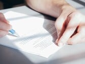Uma mão assina um documento com uma caneta esferográfica azul