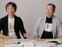 Uma captura de tela de Shigru Miyamoto e Tezuka Takashi usando camisetas do 30º aniversário de Super Mario Bros