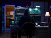 Figura encapuzada em uma configuração de várias telas executando um ataque cibernético. 
