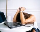 Mulher olhando para o smartphone com um laptop ao seu lado