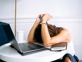 Mulher olhando para o smartphone com um laptop ao seu lado