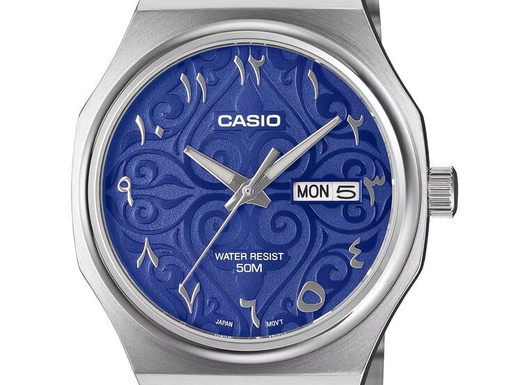Close-up do Casio MTP-E735AR-2A2V, mostrando seu mostrador azul vívido com padrão arabesco, algarismos arábicos orientais em relevo, ponteiros prateados facetados em estilo espada e indicador de dia e data às 3 horas.
