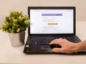Laptop sobre uma mesa exibindo um e-mail de phishing com um botão de confirmação