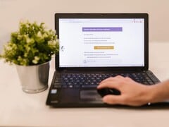 Laptop sobre uma mesa exibindo um e-mail de phishing com um botão de confirmação